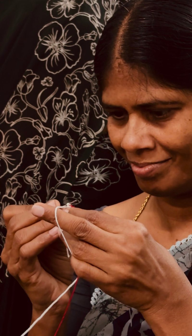 Close-up of an artisan's hands working a crochet stitch with white thread