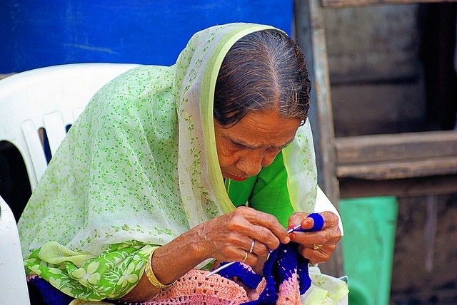 An artisan crocheting a coloured piece with a hook