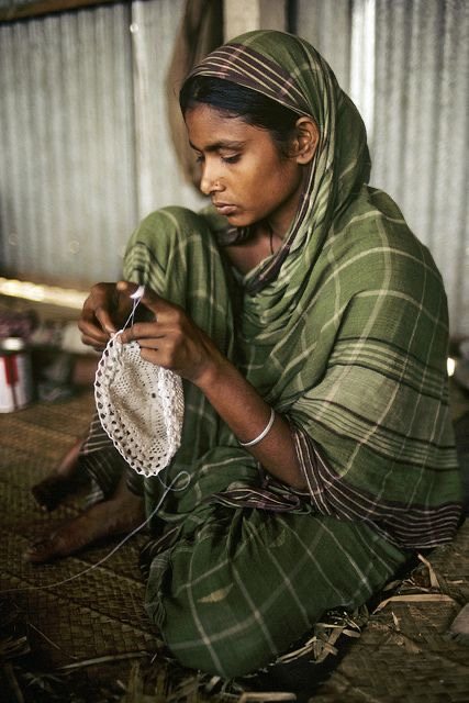 An artisan seated at work, crocheting a white piece by hand